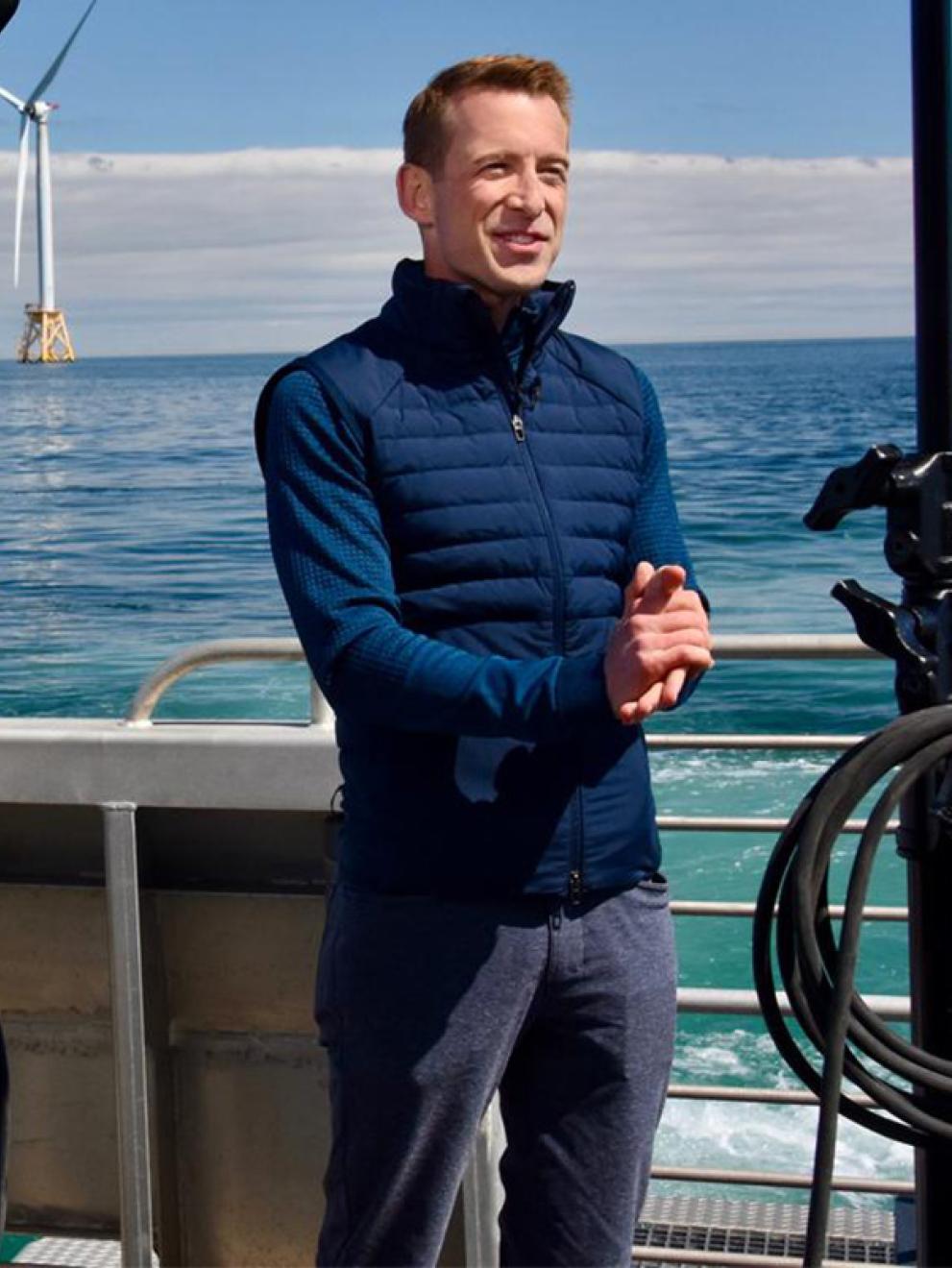 Ben Tracy on a boat with windmills in the distance.