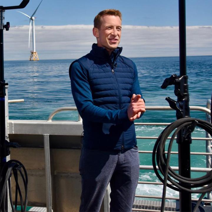Ben Tracy on a boat with windmills in the distance.