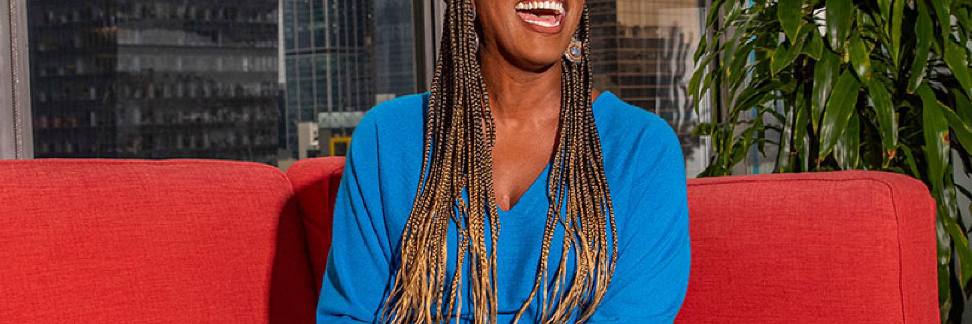 Crystal Barnes laughing on a red couch